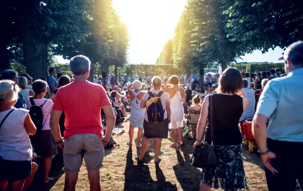 A community gathering in a park, with people sitting and standing around.