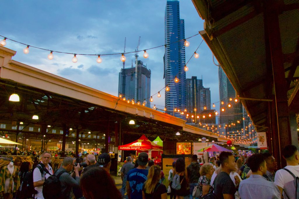People gather in a community marketplace or event location near the city center.