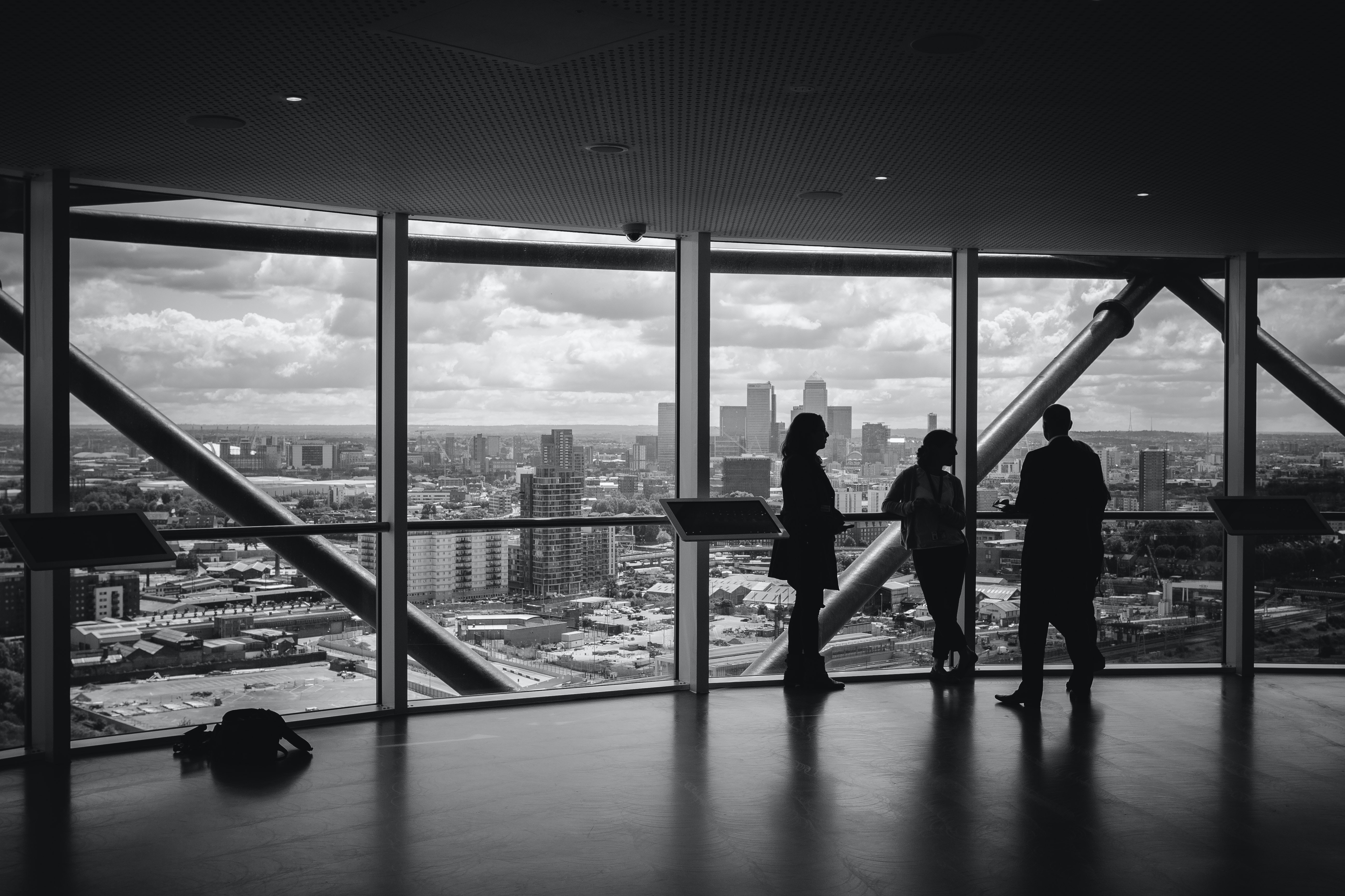 A black and white photo showing a silhouette of three people in an office high rise.
