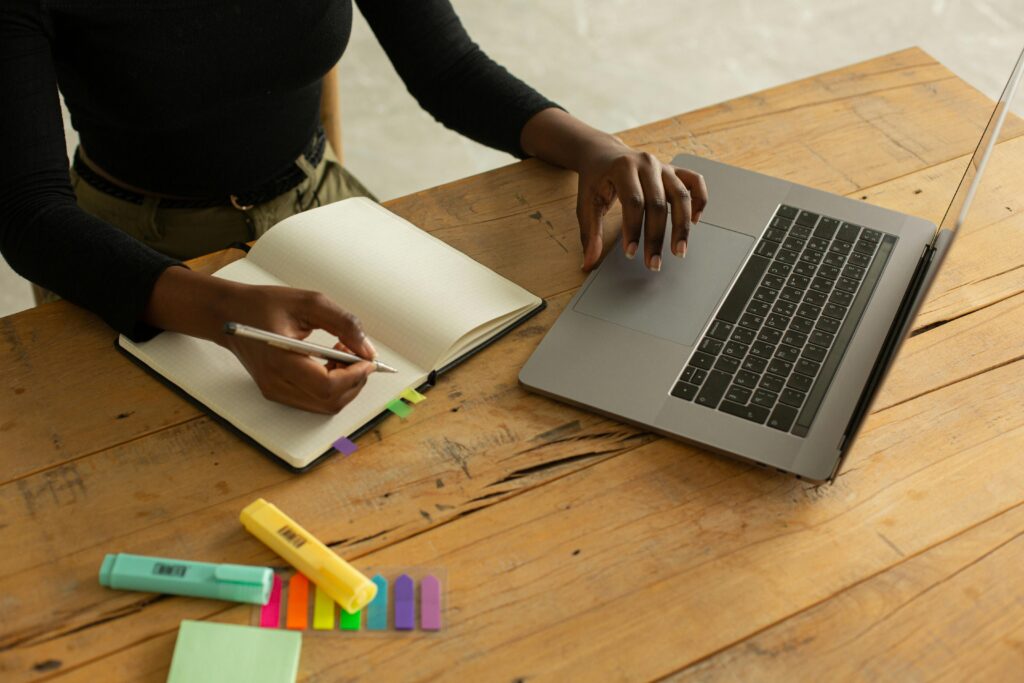 Person working on a written stakeholder plan at a laptop, with a notebook open.