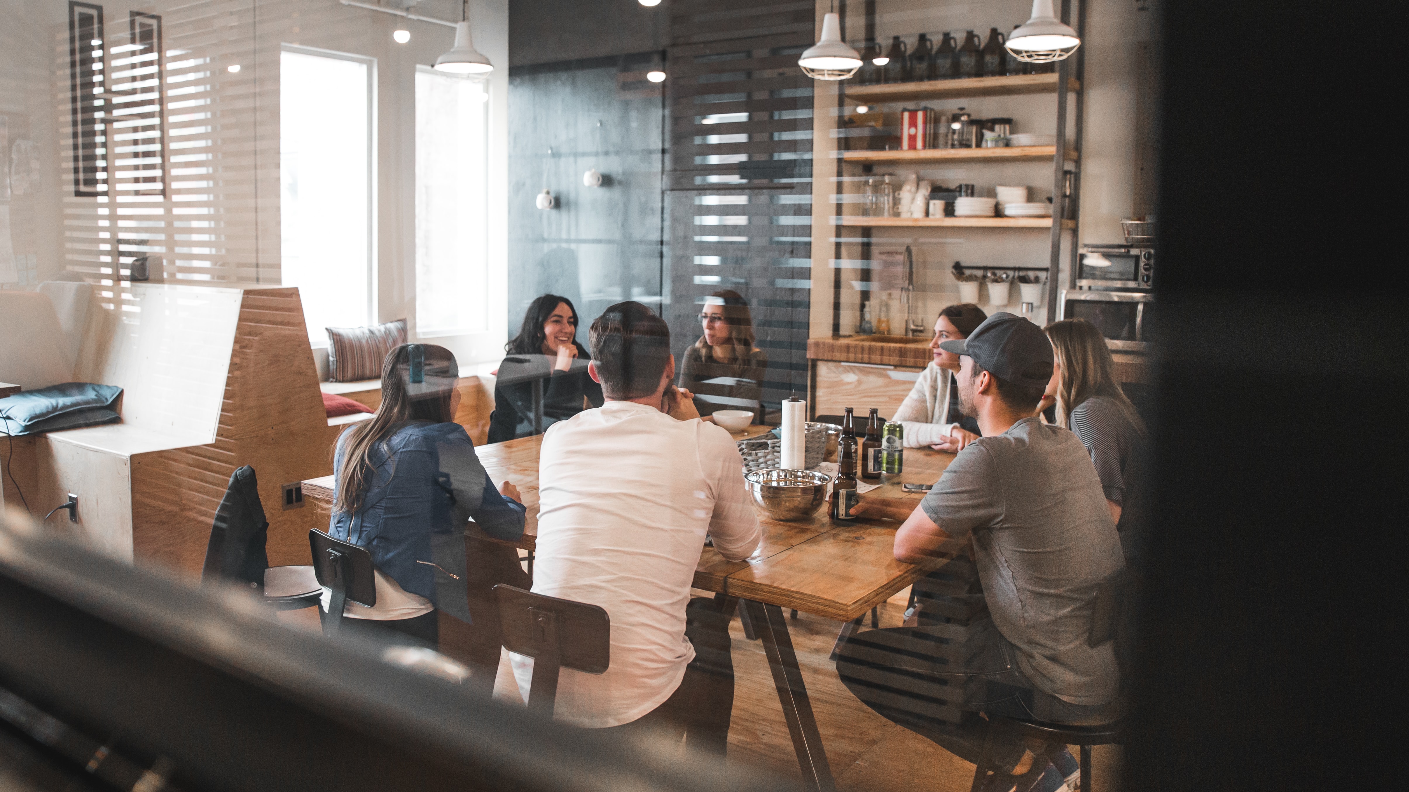 Seven people shown sitting around a table, having a discussion.