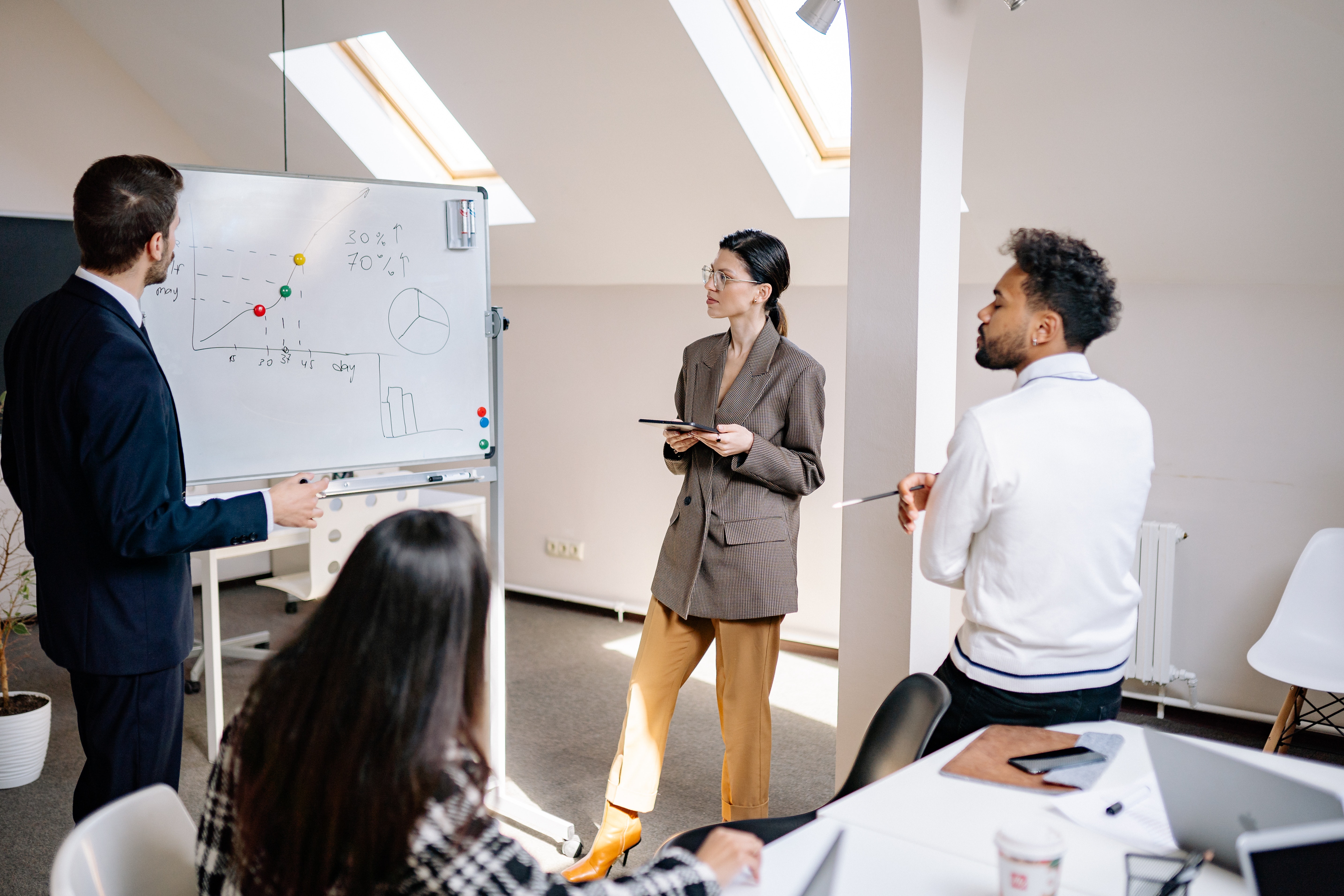 Group of four employees standing around a whiteboard that shows some charts.