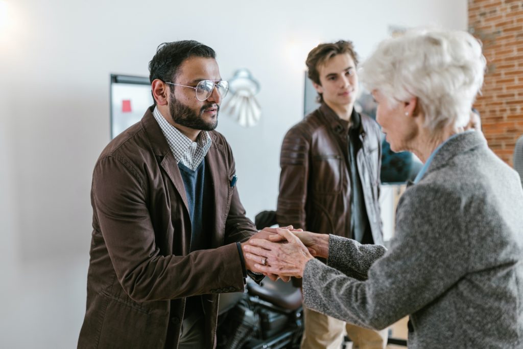 A man shakes hands with an older woman.