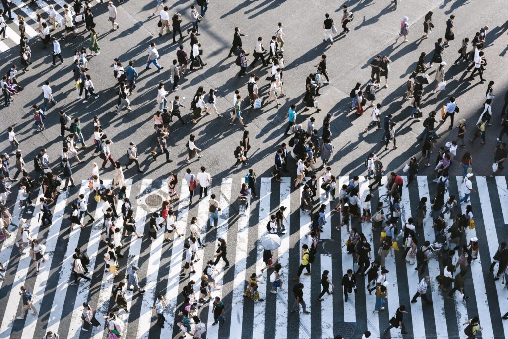 Large numbers of people walking across a street crossing.