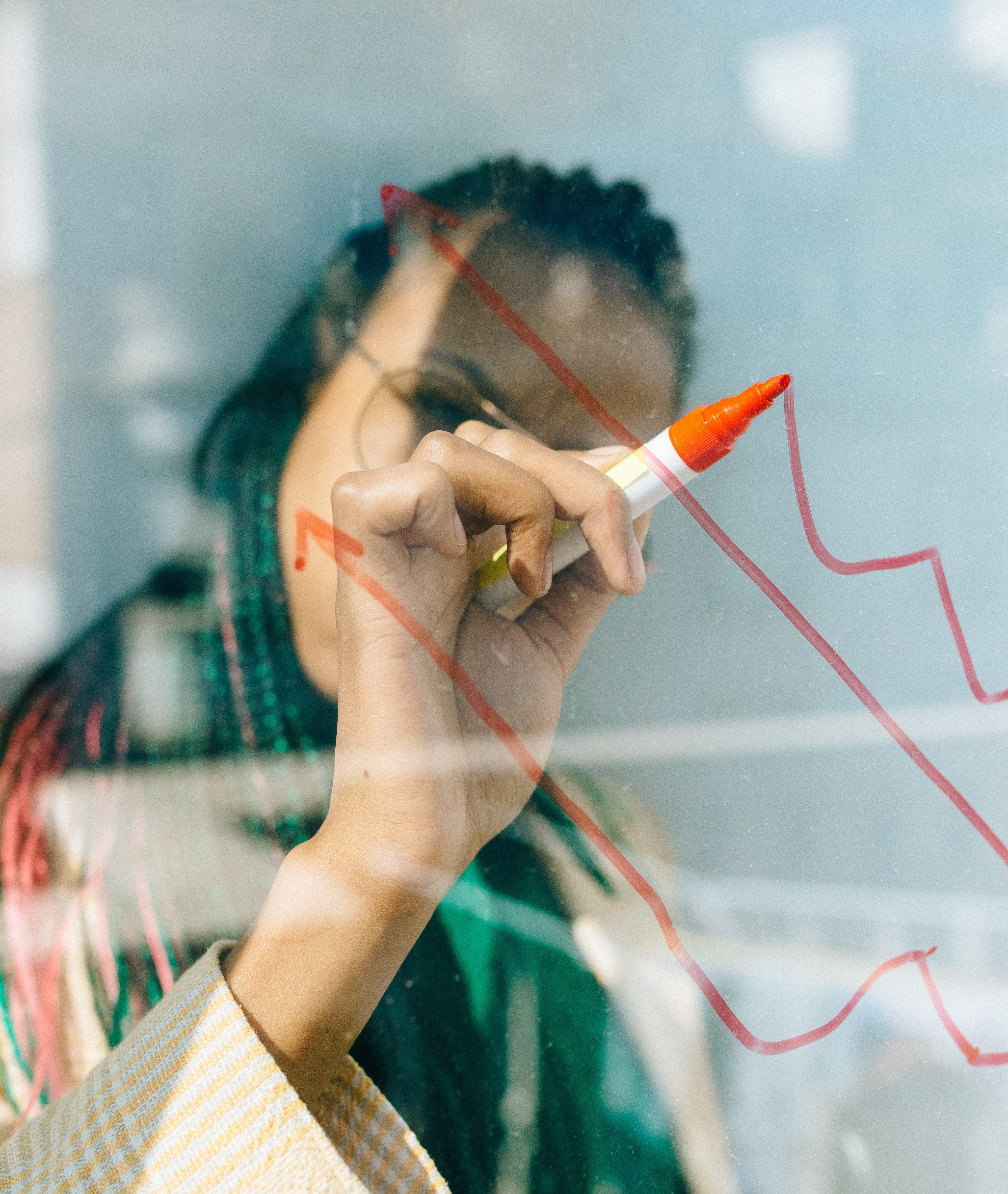 Person drawing a graph on a clear surface