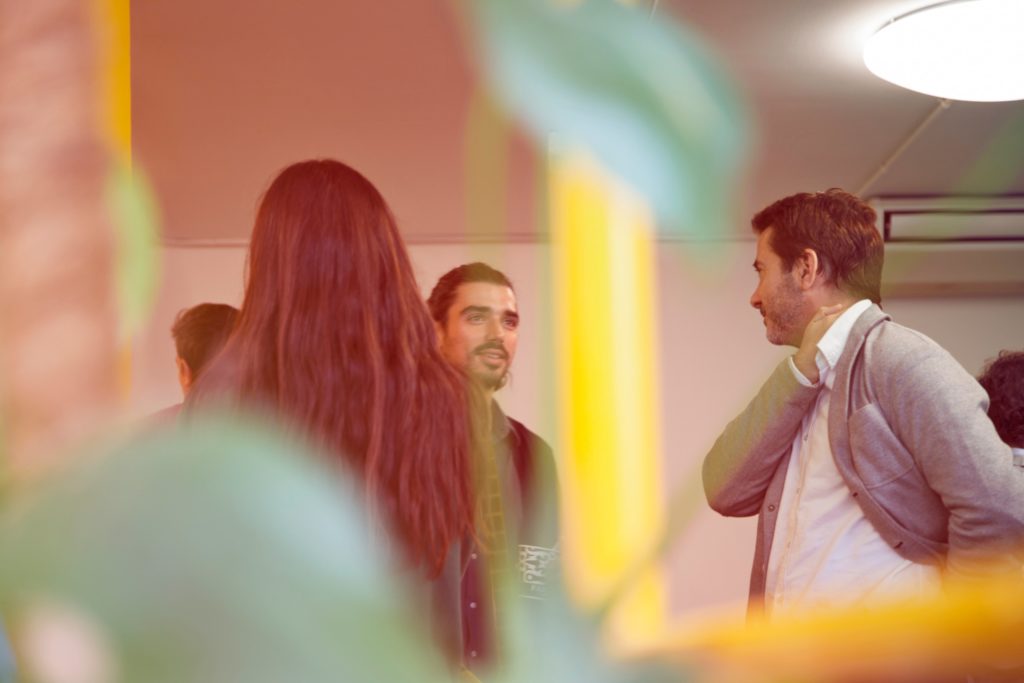 A group of people standing together indoors, having a discussion.