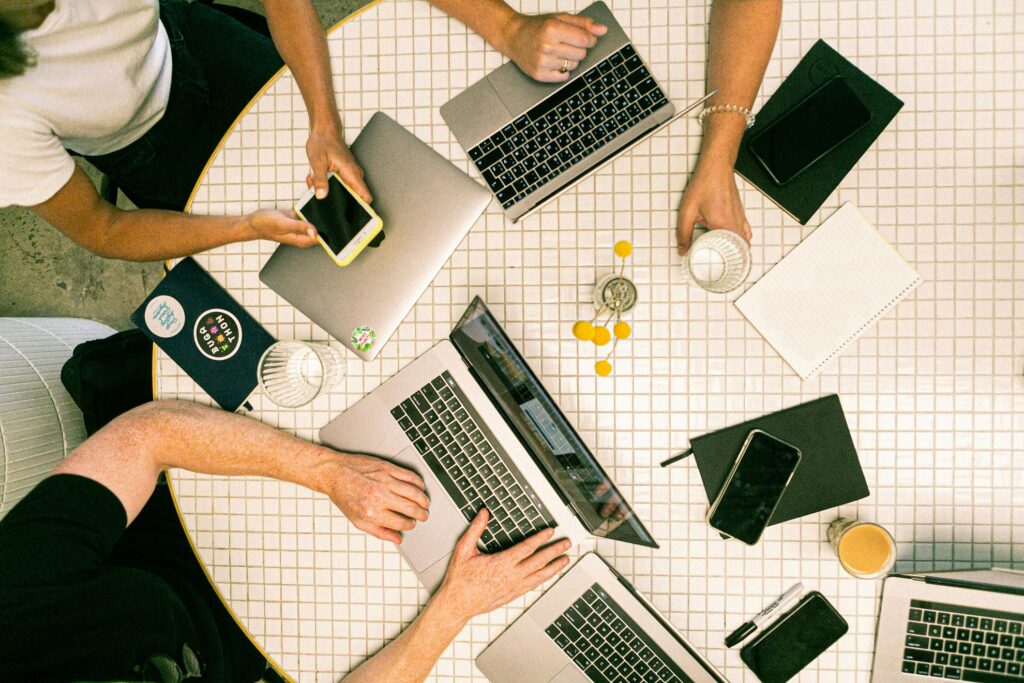 People working on phones and laptops around a table.