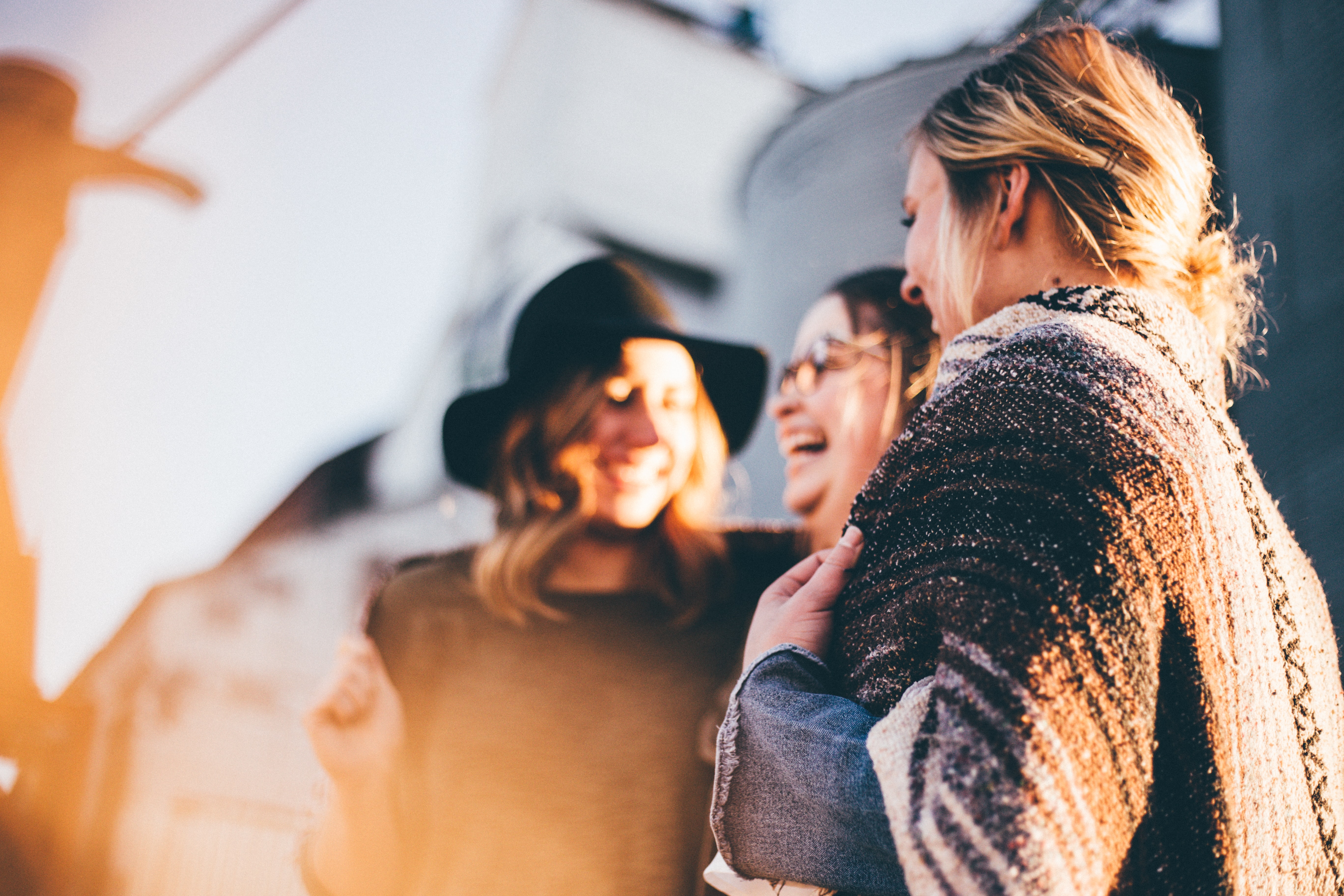 Three women stand together, smiling and laughing.