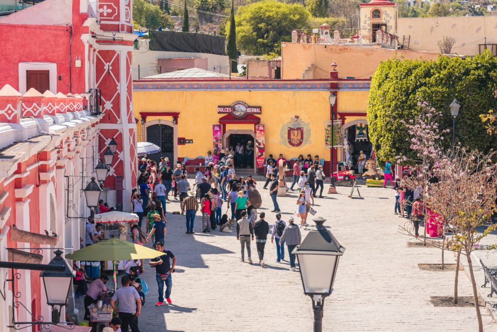 Vibrant urban street with brightly coloured buildings and people walking along pavement.