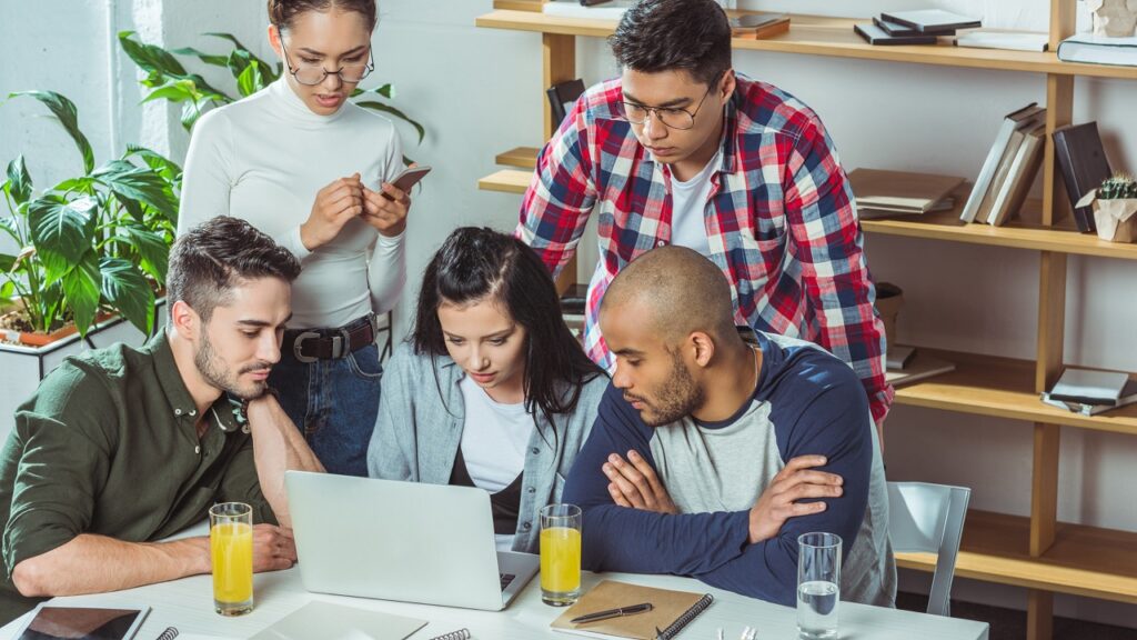 Photo of a team looking at a laptop screen together to track and analyze stakeholders.