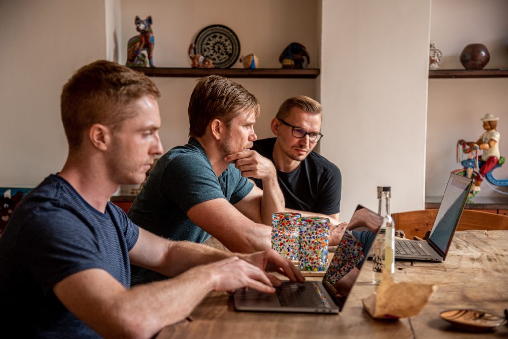 Three people sitting at a table, working on laptops