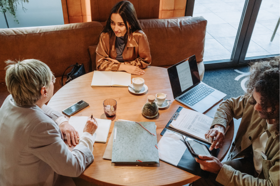 Three people at a table having a discussion and using municipal government software