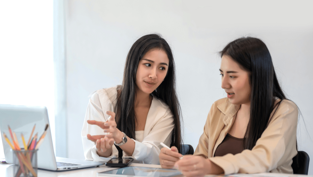 Two women seen discussing a stakeholder communications plan.